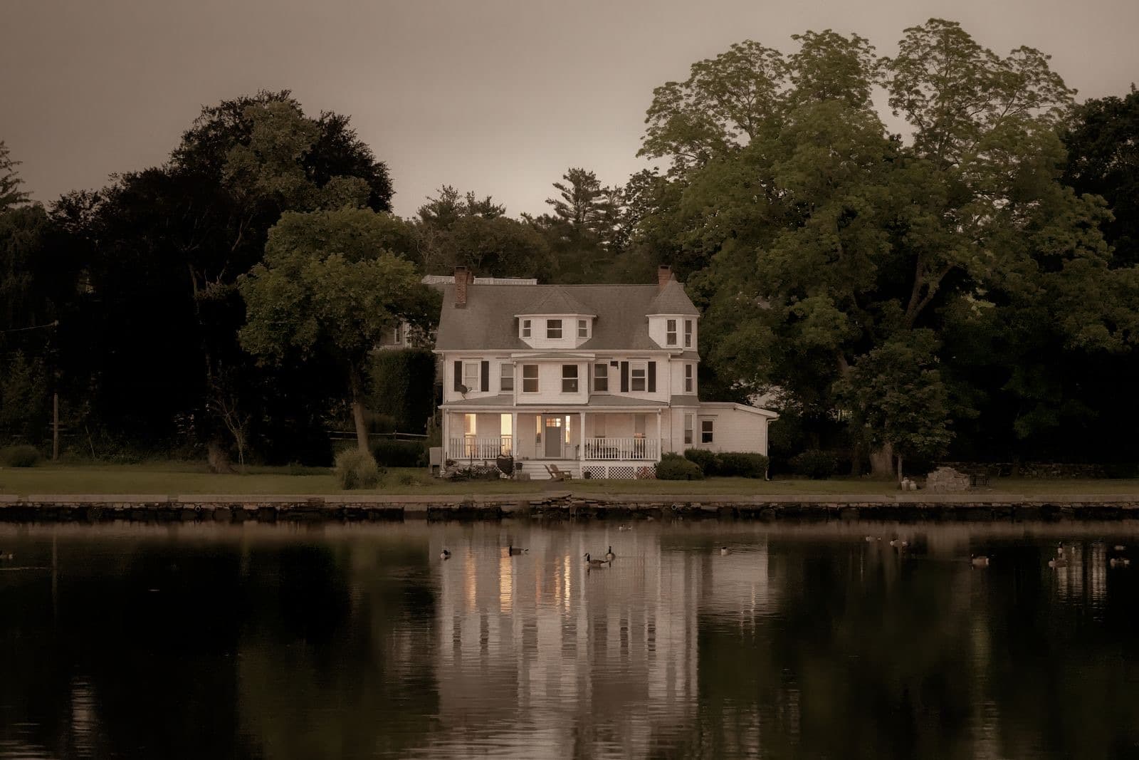 Serene colonial house reflecting on water at twilight