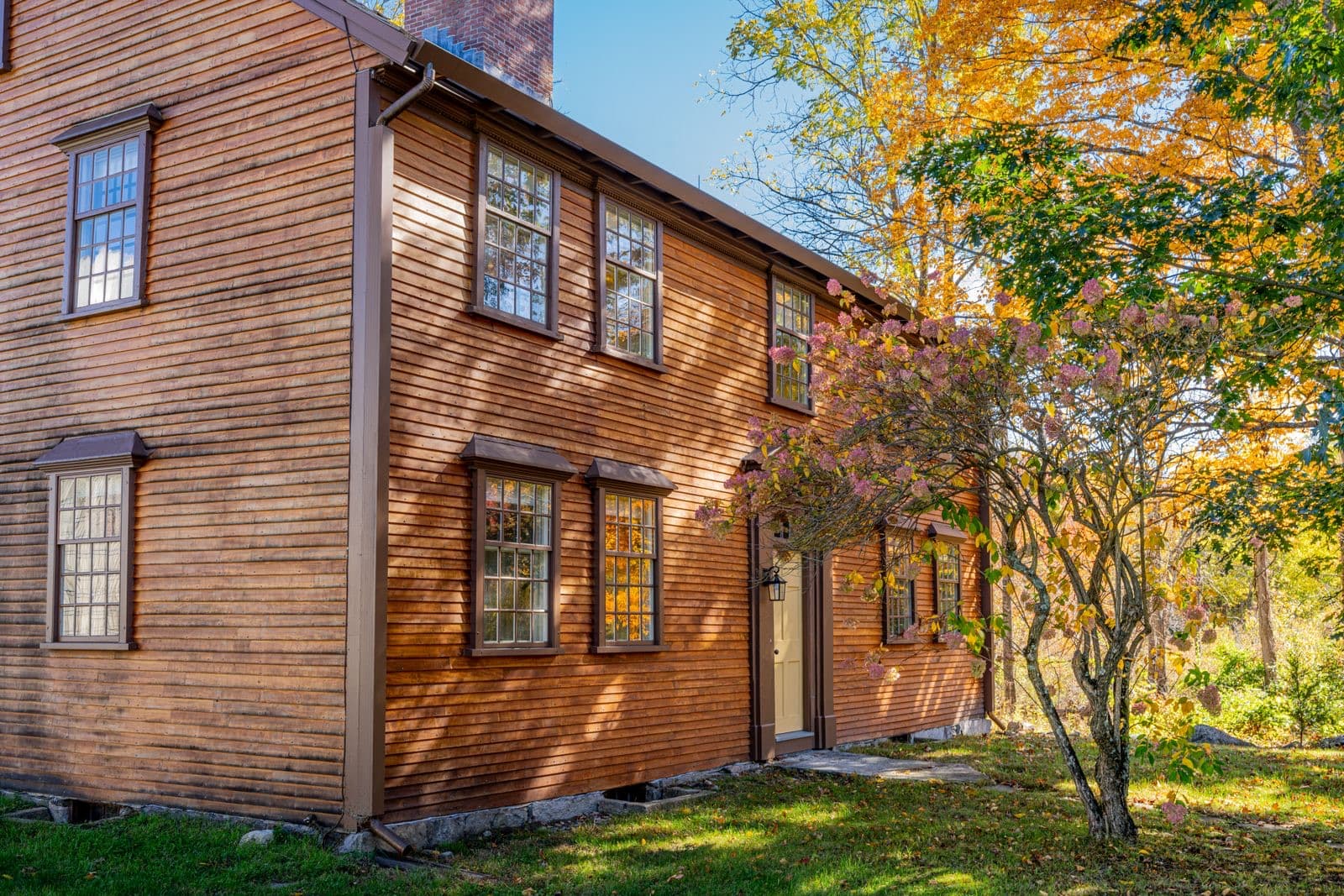 Historic wooden house surrounded by vibrant fall foliage