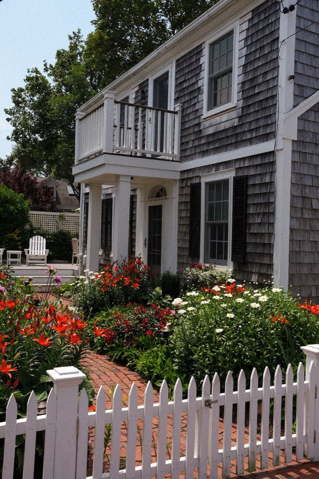 New England house with a porch, garden, and picket fence