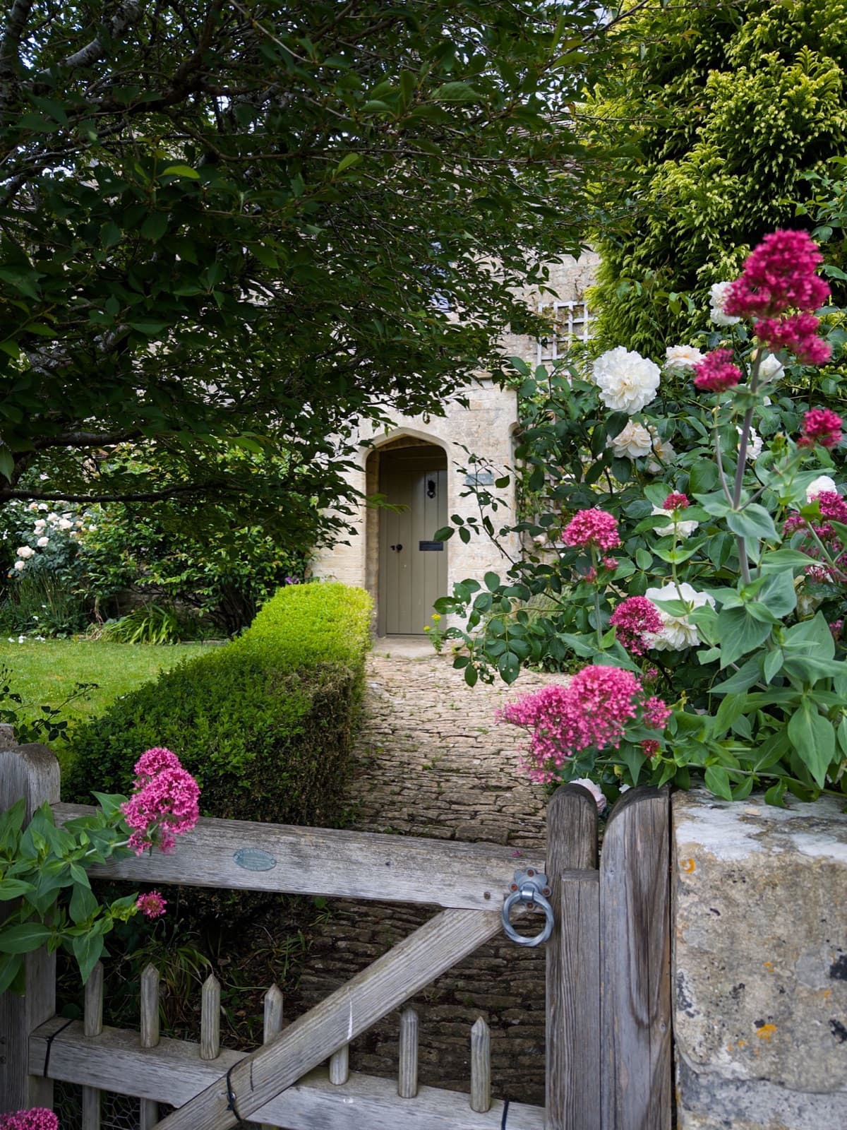 Cottage entrance framed by vibrant flowers and greenery