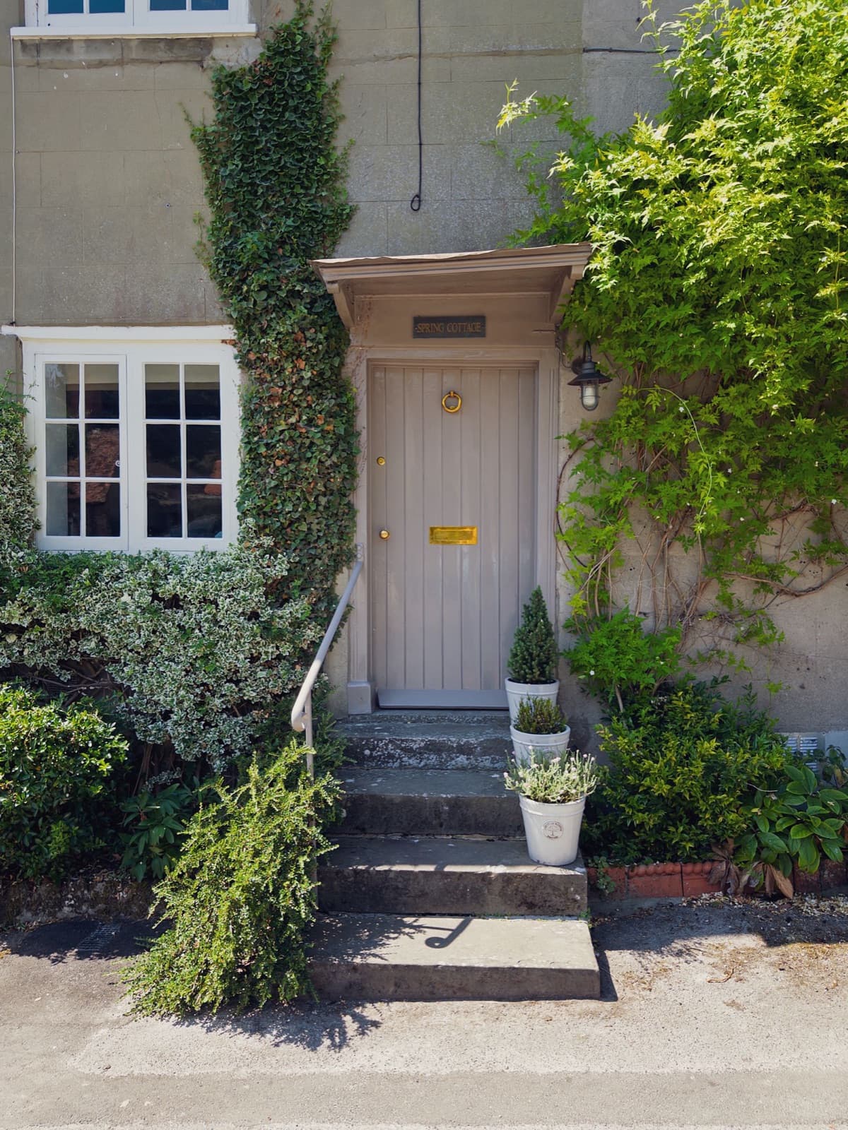 Quaint cottage entrance with greenery and potted plants