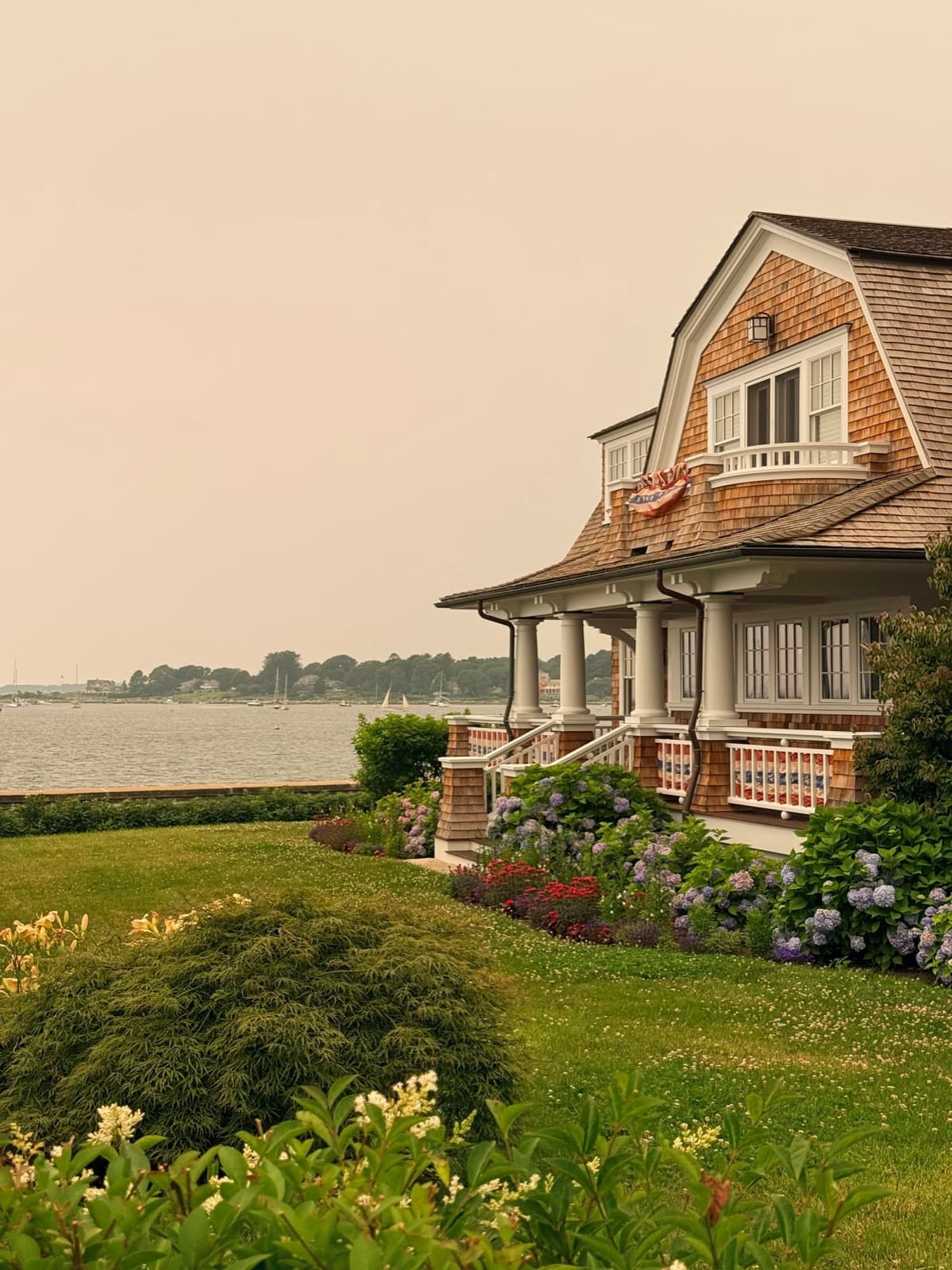Cozy coastal cottage by the water with a lush garden and flag