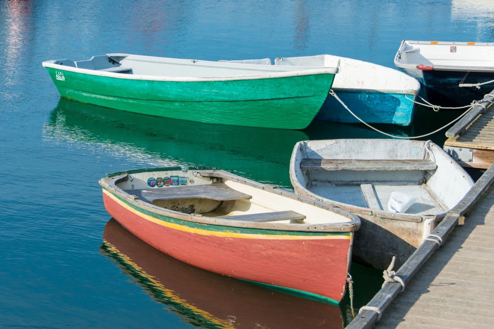 Vibrant rowboats moored at a pier, reflecting on calm water