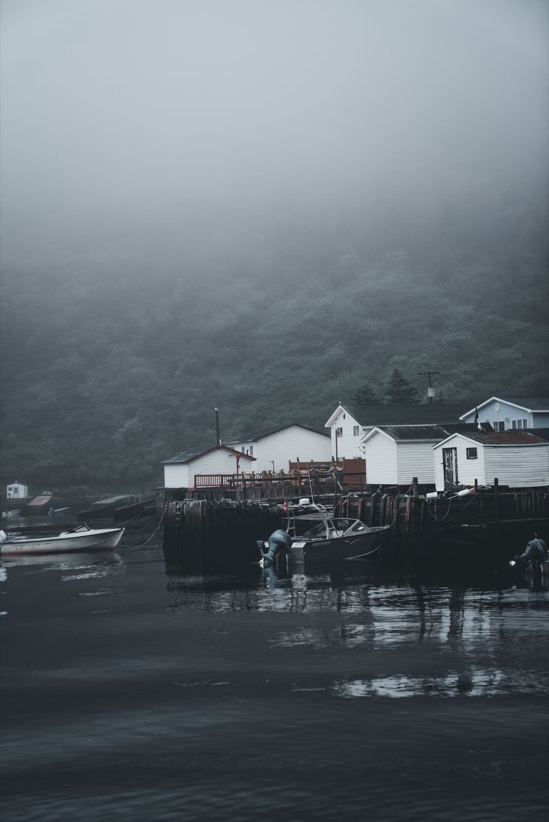 Serene foggy lakeside village with boats docked along the shore