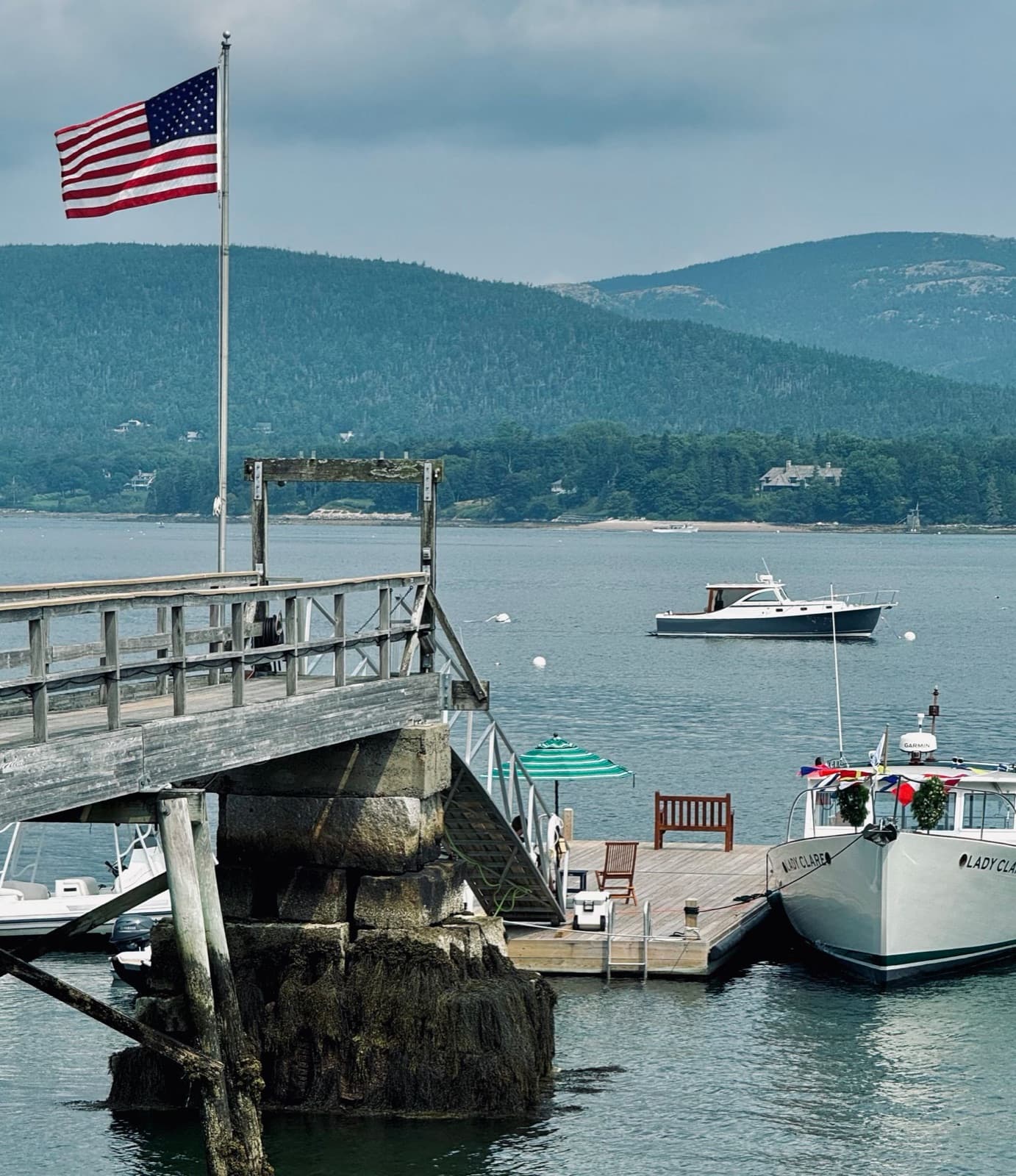 Dock with an American flag, boats, and a scenic backdrop