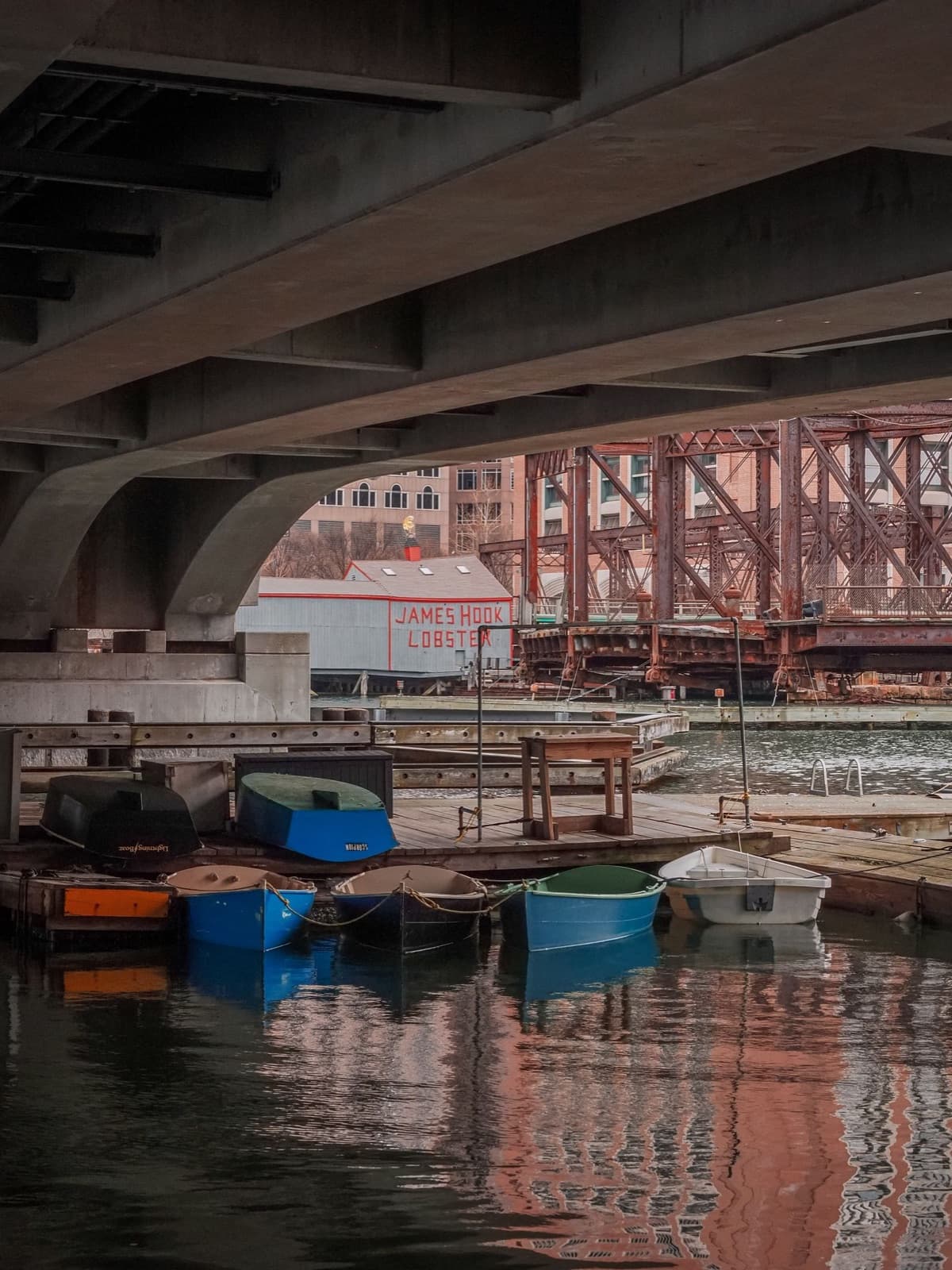 Small boats docked under a bridge near the harbor
