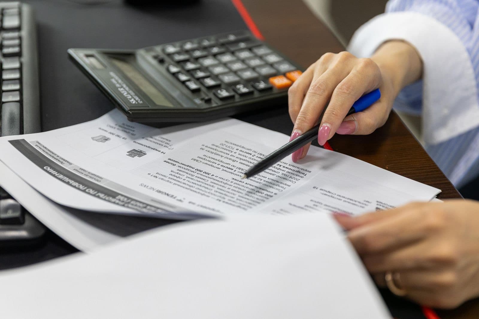 Close-up of a hand reviewing financial documents with a calculator