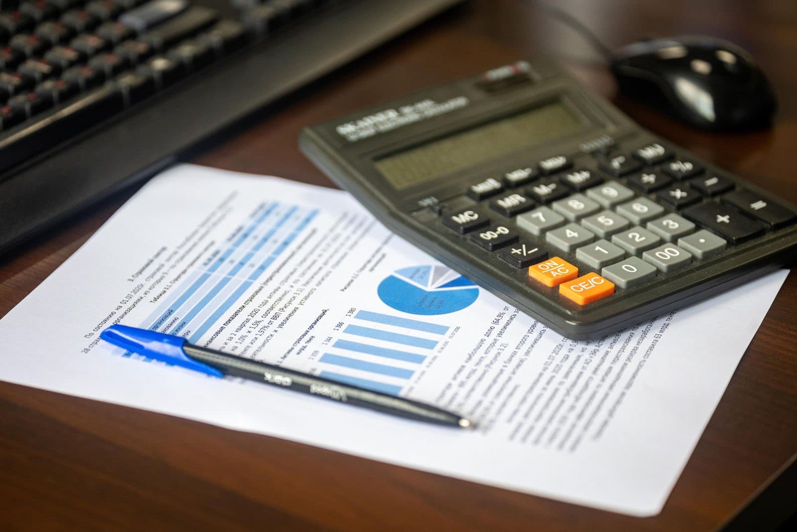 Desk with a calculator, financial report, and pen
