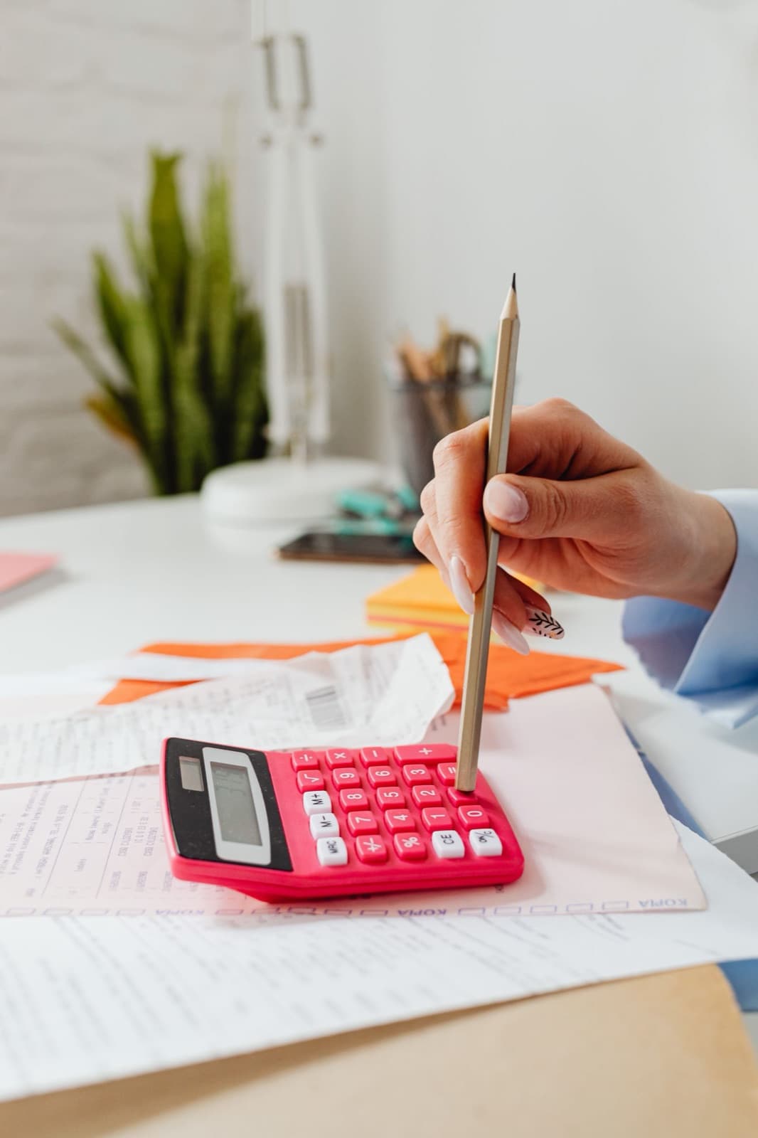 Close-up of a hand with a pencil and calculator