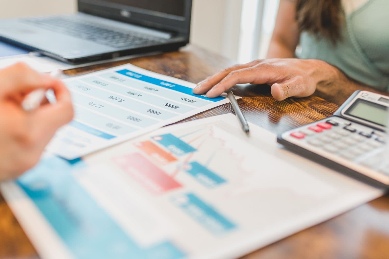 Hands at a desk with financial graphs and a calculator
