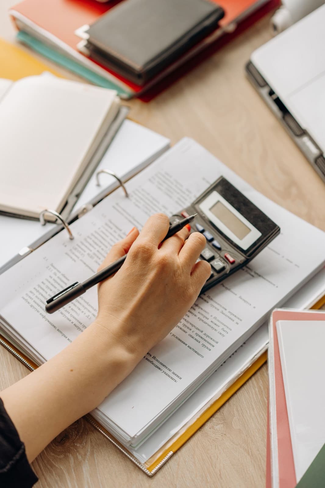 Close-up of a hand using a calculator on documents