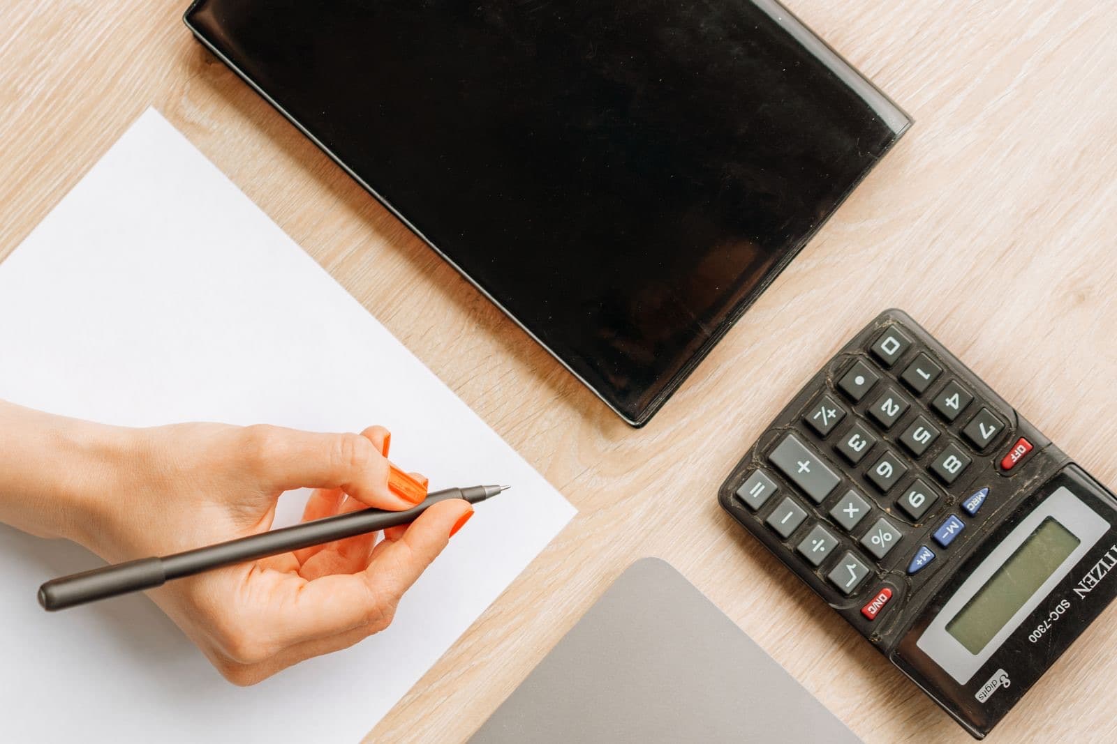 Top view of a hand writing on a minimalist office desk