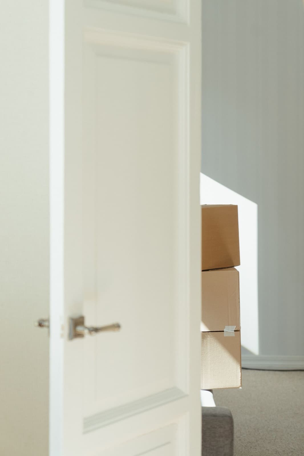 Open door revealing stacked cardboard boxes in a sunlit interior