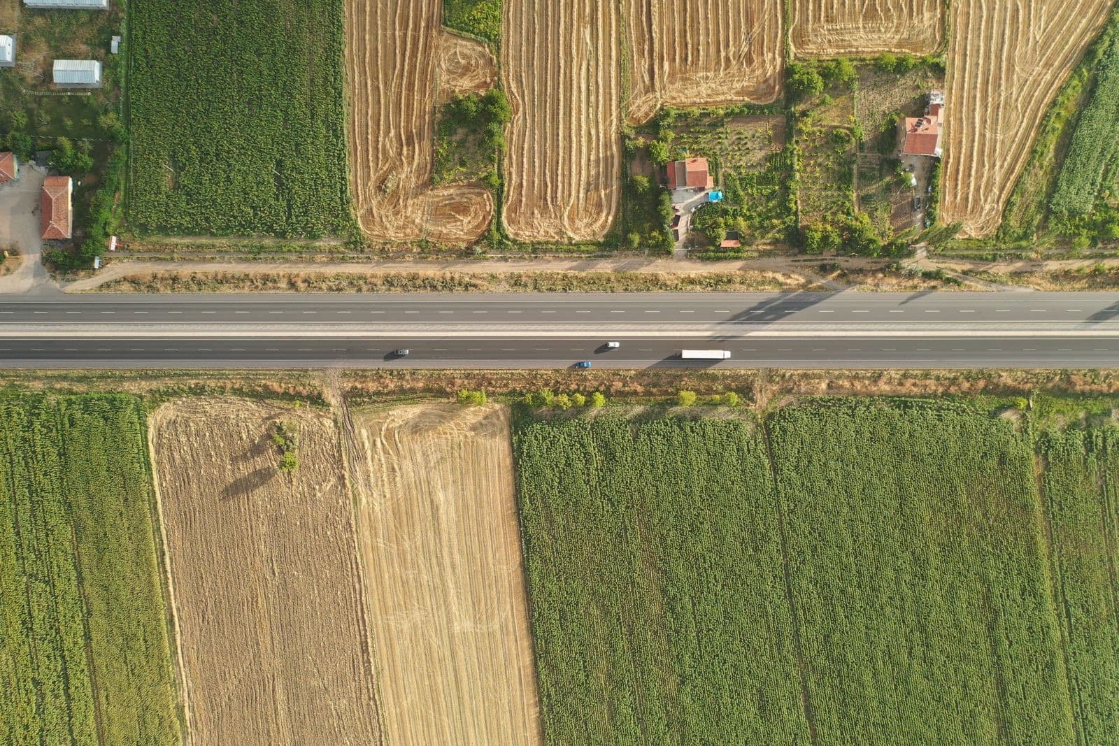 Aerial shot of a rural road through lush fields