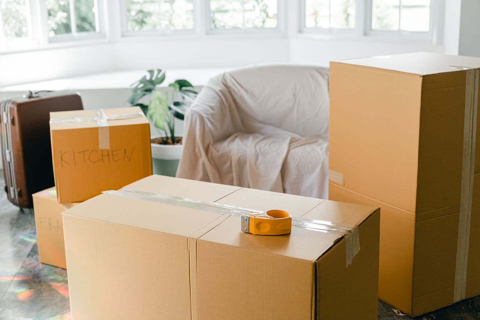 Stacked moving and packing boxes in an empty, sunlit living room