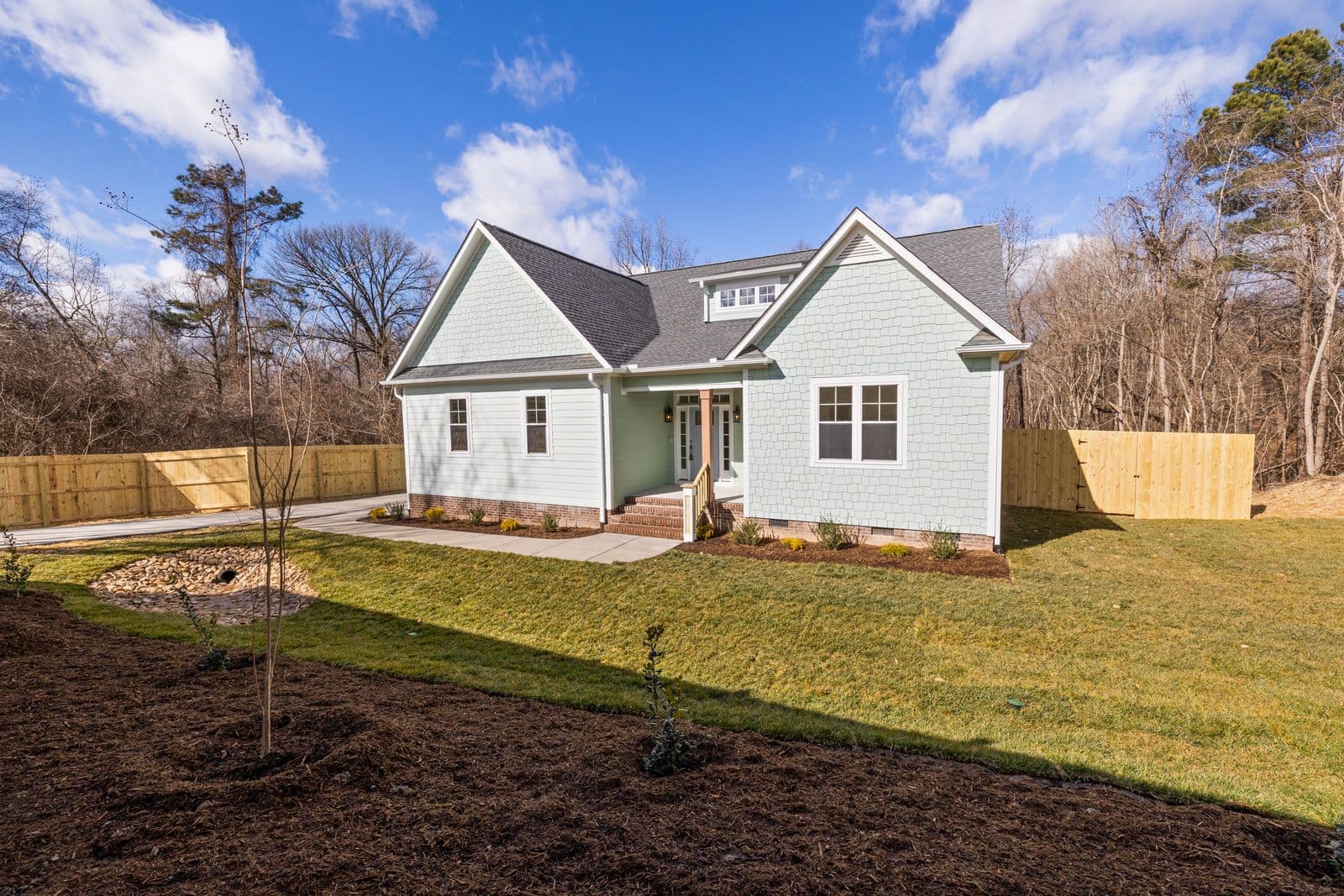 Single-story bungalow home exterior with driveway and lawn under a blue sky