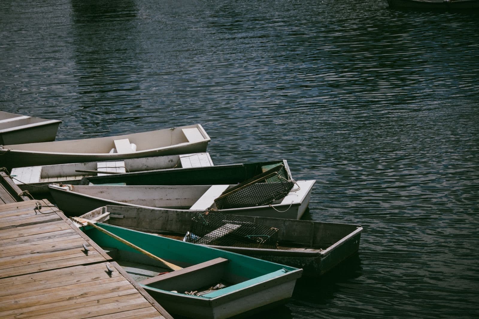 Wooden rowboats tied up at a weathered dock on the water